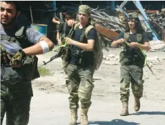  ?? (Abdalrhman Ismail/Reuters) ?? FREE SYRIAN ARMY fighters walk with their weapons in the Ramousah area southwest of Aleppo, Syria, last week.