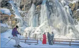  ?? PTI ?? Tourists in the backdrop of a frozen waterfall at Tangmarg in Baramulla district on Thursday.