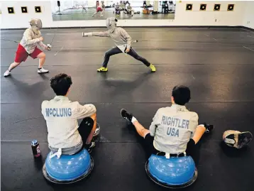  ?? [JOSHUA A. BICKEL/DISPATCH PHOTOS] ?? Blake Bradford, left, and Carey Yi, battle during a match as Gavin Mcclung, bottom left, and Sam Rightler watch during a saber fencing class at Columbus Fencing & Fitness in Dublin.