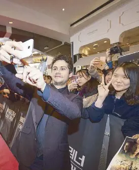  ??  ?? Dylan O’Brien obliges a Korean fan’s request for a selfie… and signs autographs at the red carpet event at the IFC Mall Cinema in Seoul. Right: Ki Hong Lee also does the same.