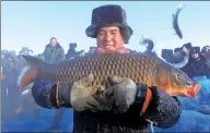  ??  ?? A local man shows off his catch during a winter fishing competitio­n at Fuhai county’s Ulungur Lake.