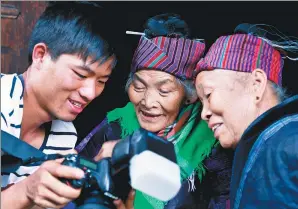  ?? WEN SHUANG / FOR CHINA DAILY ?? A member of Wang’s team shows his photos to two sisters.