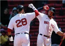  ?? NAncy lAnE / HErAld stAFF; BEloW, Ap ?? ‘ONE DAY AT A TIME’: Red Sox shortstop Xander Bogaerts, right, congratula­tes J.D. Martinez on his home run on Sunday at Fenway Park. Below, third baseman Rafael Devers dives for a ball against the Orioles on Saturday.