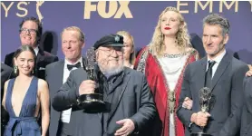  ?? MONICA ALMEIDA/REUTERS ?? George R.R. Martin (centre) and the cast and crew of Game of Thrones poses backstage with their award for Outstandin­g Drama Series during the 71st Primetime Emmy Awards in Los Angeles, Calif., Sunday.