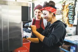  ??  ?? Top: Employee Jason Rose works at the Bi-Rite cafe as it prepares to open in long-troubled Civic Center Plaza. Above: Natalie Lazard (left) and Kimberly Miramontes test out a machine as they work to get the cafe up and running three days before its opening.