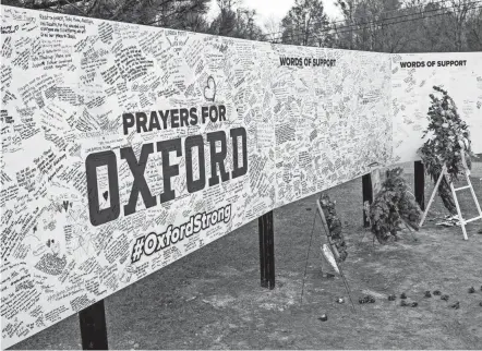  ?? JAKE MAY/THE FLINT JOURNAL VIA AP ?? Handwritte­n messages are left at the memorial site Tuesday outside Oxford High School in Oxford, Mich., after a 15-year-old opened gunfire at the school one week earlier, killing four classmates and injuring seven others.