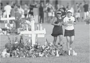  ?? MIKE STOCKER/AP ?? Runners pass a memorial for the victims of the Feb. 14 Marjory Stoneman Douglas High School shooting, in Parkland, Fla., on Wednesday.