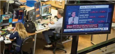  ?? – AP ?? Cheaper currency: A tV screen reads that ‘Pound Sterling plummets to a 30-year low’ following the Brexit vote as traders, background, work at the euronext Amsterdam Stock exchange. In Malaysia, it dropped to less than 5.5 against the ringgit.