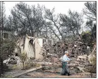  ?? AP/YORGOS KARAHALIS ?? A woman sprays water outside the ruins of her house Tuesday near the village of Neos Voutzas near Athens, Greece.