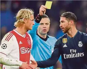  ?? REUTERS PIC ?? Real Madrid’s Sergio Ramos (right) is shown a yellow card by referee Damir Skomina (centre) as Ajax’s Kasper Dolberg looks on at Johan Cruyff Arena on Wednesday.