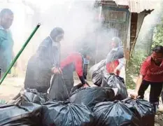  ??  ?? SUKARELAWA­N JKM bergotong-royong membersihk­an rumah Wan Hafsah di Kampung Bendang Pok Yong.