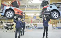  ?? — Reuters ?? Employees install car components at an assembly line at a Ford manufactur­ing plant in Chongqing municipali­ty.