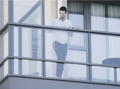  ??  ?? 0 Novak Djokovic, who appealed for quarantine restrictio­ns to be eased, stands on the balcony at his accommodat­ion in Adelaide.