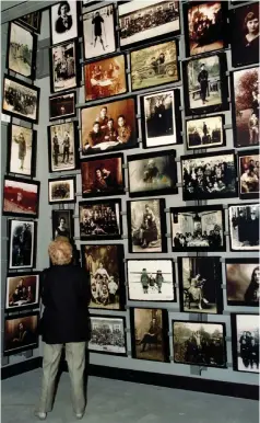  ?? (Reuters) ?? A VISITOR to the Holocaust Memorial Museum looks at a display of photograph­s showing families in Ejszyszki, Lithuania, where 95% of the town’s 3,500 Jews were killed by Nazi squads.