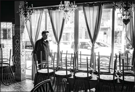  ??  ?? Top: When COVID first hit, people were seldom seen on the streets. This man’s solitude was striking on the Lakeshore. Bottom: Normally, the Lula Lounge on Dundas would be alive with live music, jazz and salsa dancing. Here, co-owner Jose Nieves in the now silent space amid its stacked chairs.