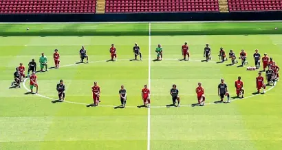  ??  ?? Liverpool players take a knee at the centre circle of Anfield.