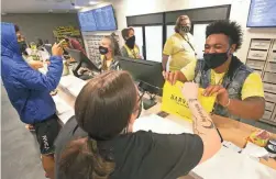  ?? DAVID WALLACE/THE REPUBLIC FILE ?? Sione Palelei, right, hands a bag of cannabis products to a customer at Harvest marijuana dispensary in Scottsdale earlier this year.