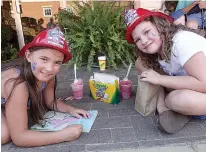  ??  ?? n Laynie Daniels, left, and Emma Williams are enjoying the Music on Main Street on Friday evening in downtown Linden. They liked the colors, fire hats and snow cones.