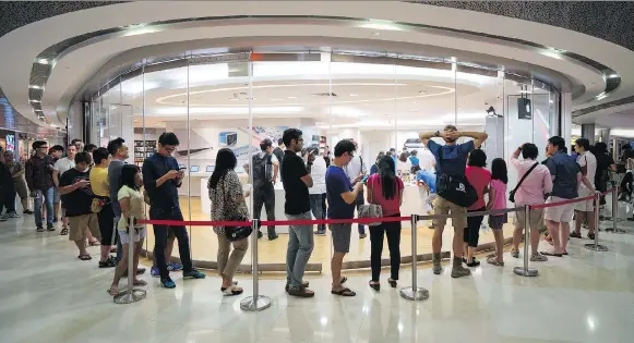  ?? BRYAN VAN DER BEEK /BLOOMBERG ?? Customers wait in line to look at Apple Watch devices on display at a Singapore mall. Singapore is boldly testing new waters with its launch of a five-year plan this year to streamline its infrastruc­ture and reduce bureaucrac­y with cutting-edge technology. At the same time, the city-state’s government insists it takes data privacy seriously.