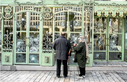  ?? AP ?? Bystanders take snapshots of the smashed windows of the famed tea salon Laduree on the Champs Elysees the day after it was vandalized during the 18th straight weekend of demonstrat­ions by the yellow vests, in Paris.