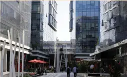  ?? (Reuters) ?? MEN WALK near high-rise buildings in a hi-tech business area of Tel Aviv in May.