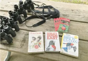  ?? ?? Binoculars and books about birding occupy a picnic table Tuesday at Eggers Grove Forest Preserve.