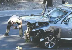  ?? GENE BLEVINS / REUTERS ?? A Los Angeles County Sheriff ’s deputy inspects
the SUV that Tiger Woods was driving.