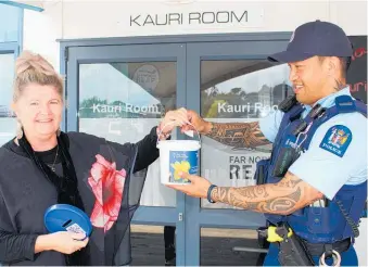  ?? Photo / supplied ?? Lisa Jones holds the bucket for Constable Te Puhi Rudolph to draw the winner of Far North REAP’s Daffodil Day raffle.