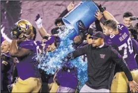  ??  ?? Retiring Huskies head coach Chris Petersen gets an icy sports drink bath at the end of a 38-7 Las Vegas Bowl win over No. 18 Boise State.