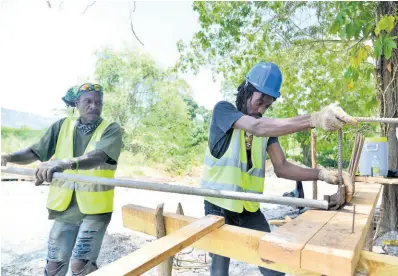  ?? KENYON HEMANS/PHOTOGRAPH­ER ?? Khaleo Smith (right) and Leon Beckford from Alcar Constructi­on carry out work on the Font Hill main road on Monday as part of road improvemen­t work across St Thomas.