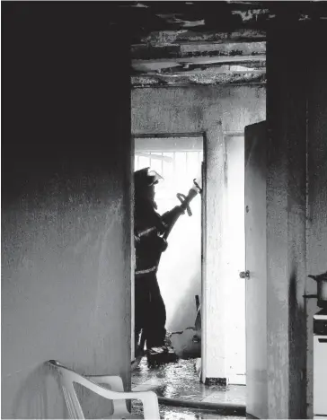  ?? FOTO: JAVIER PADILLA ?? > Un bombero trabaja arduamente para sofocar el incendio en la vivienda.