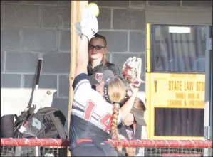  ?? RICK PECK/ SPECIAL TO MCDONALD COUNTY PRESS ?? McDonald County third baseman Adasyn Leach stretches over the fence guarding the Nevada dugout in an attempt to catch a foul pop-up during the Lady Mustangs’ 8-0 win on Sept. 24 at MCHS.