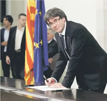  ?? — Gambar Reuters ?? TANGGUH: Puigdemont menandatan­gani pengisytih­aran kemerdekaa­n di Parlimen Catalonia di Barcelona, kelmarin.