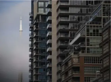  ?? COLE BURSTON/THE CANADIAN PRESS ?? The CN Tower peeks through the clouds, seen beside the condos of Liberty Village.