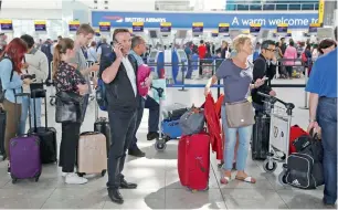  ??  ?? People wait with luggage at British Airways check-in desks at Heathrow Airport in London.
— Reuters