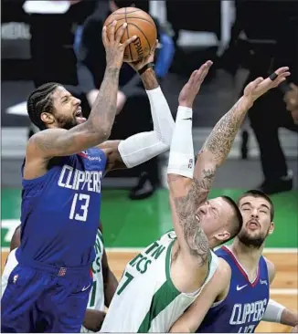  ?? Elise Amendola Associated Press ?? PAUL GEORGE, shooting over Boston’s Daniel Theis as Clippers teammate Ivica Zubac looks on, scored 32 points but struggled in the fourth quarter, making just two of 10 shots.