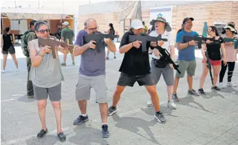  ??  ?? READY FOR ACTION: Foreign tourists train with wooden guns and watch an Israeli instructor demonstrat­ing how to use a dog to neutralise an attacker during a simulation at the Caliber 3 shooting range.