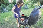  ?? TINA PHAN / AMERICAN-STATESMAN ?? Addie Broyles tops pizza dough with mushrooms, mozzarella and grilled tomatoes on the grill in the backyard of her home.