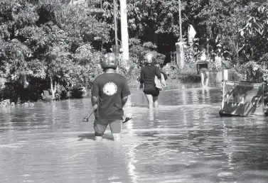  ??  ?? RESIDENTS cross the flooded street of Castro Village in Barangay Bago Aplaya, Talomo District, on Friday after a night of heavy rains in the southern part of the city. BING GONZALES