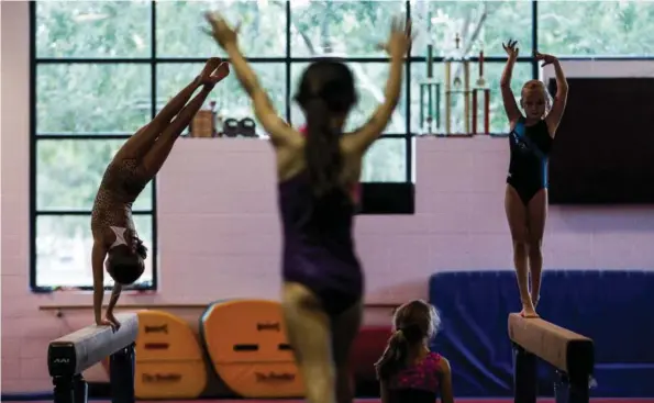  ?? Michael Ciaglo / Houston Chronicle ?? Marisa Bishop, 9, left, dismounts a balance beam during gymnastics class at Evelyn Rubenstein Jewish Community Center of Houston. The center is at the middle of the precinct with Houston’s highest voter turnout.