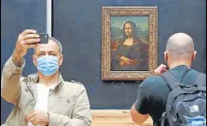  ?? AFP ?? A visitor wearing a face mask takes a selfie in front of Leonardo da Vinci's masterpiec­e Mona Lisa at the Louvre Museum in Paris.