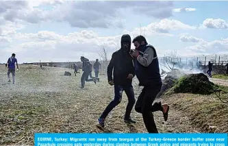  ??  ?? EDIRNE, Turkey: Migrants run away from teargas at the Turkey-Greece border buffer zone near Pazarkule crossing gate yesterday during clashes between Greek police and migrants trying to cross to the Greek side. —AFP