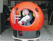  ?? GREG GILBERT, SEATTLE TIMES ?? Jeanne Johnson and her dog, Trixie, peer out of her tsunami survival pod at her home in Ocean Park, Washington.