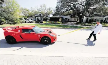  ?? JEFFEREE WOO Tampa Bay Times/TNS ?? Dentist Mike Foley pulls a car with his teeth at his residence in Tampa. Foley wants to break the speed record for pulling a 2,000-pound car by the teeth for 30 meters. He has done it in 30 seconds. The world record is 18.13 seconds.