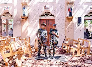  ?? — Reuters photo ?? Sri Lankan military stand guard inside a church after an explosion in Negombo.