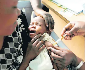  ?? AP ?? A mother holds her baby receiving a new malaria vaccine as part of a trial at the Walter Reed Project Research Center in Kombewa, Western Kenya.