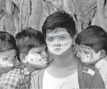  ?? INDRANIL MUKHERJEE/GETTY-AFP ?? Students with their faces painted with the colors of India’s flag pay tribute to front-line workers fighting the spread of COVID-19 on Sunday in Mumbai, India. The South Asian nation of more than 1 billion people ranks second in the world with more than 10 million confirmed infections. More than 153,000 there have died from COVID-19.