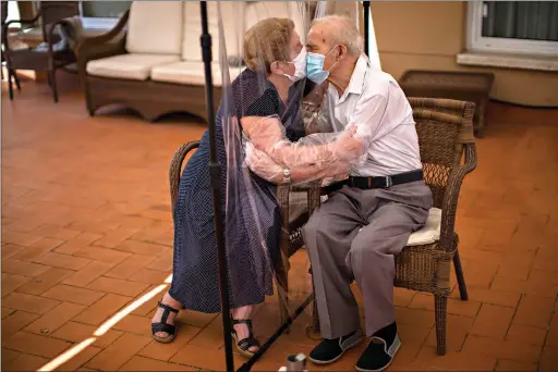  ??  ?? Agustina Cañamero, 81, and Pascual Pérez, 84, hug and kiss through a plastic screen June 22 at the Ballesol Puig i Fabra nursing home in Barcelona, Spain. Even when it comes wrapped in plastic, a hug can convey tenderness and relief, love and devotion. The fear that gripped Cañamero during the 102 days she and her 84-year-old husband spent physically separated during Spain’s coronaviru­s outbreak dissolved the moment the couple embraced through a screen of plastic film. (AP Photo/Emilio Morenatti)