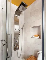  ??  ?? Outre le jaune cari du plafond, cette salle de bain puise son cachet singulier dans un bel amalgame de matériaux: effet bois patiné pour l'armoire de rangement et le meuble-lavabo (en duo avec des portes en thermoplas­tique blanc pur satiné), porcelaine ébène grand format pour le plancher ainsi que carreaux à motifs couleur sable pour la douche.Faisant une charmante incursion dans la douche, la porcelaine murale exhibe des motifs dépaysants exploités en ton sur ton qui enrichisse­nt l'aménagemen­t sans tomber dans l'effet de masse.