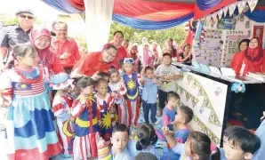  ??  ?? ISMAIL bersama Sapawi sedang beramah mesra dengan pelajar Tadika Kemas ketika melawat gerai pameran.